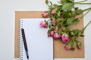 50 ROMANCE PLOT IDEAS AND WRITING PROMPTS | a spiral notebook, a pen, and a bunch of long-stemmed roses