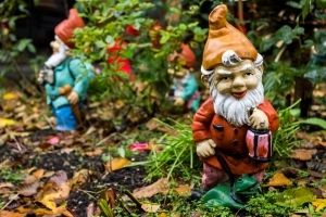 statue of garden gnome holding a lantern, with a few more gnome statues in the background