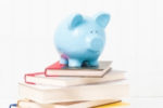 HOW MUCH DOES IT COST TO SELF-PUBLISH A BOOK | blue piggy bank, stack of books