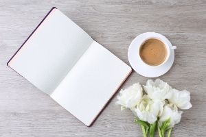 THINGS TO WRITE ABOUT YOURSELF | 100 writing prompts for self discovery | open journal, white flowers, cup of coffee