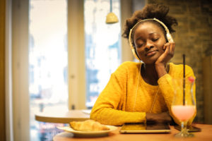 young woman in restaurant blissfully listening to music - how to describe happiness in writing