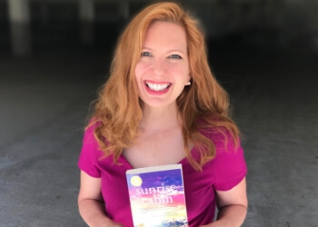 Stacey Donovan, romance author, holding a copy of her novel Sunrise Cabin.