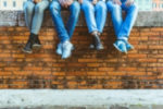 50 young adult novel writing prompts | a group of friends in blue jeans sitting on a wall