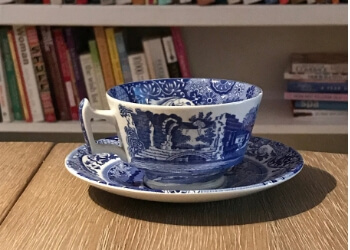 a teacup and saucer with bookshelves in the background