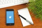 Image of phone with Twitter logo, paper and pencil, and keyboard | What Is #PitMad? I'll Tell You, and Give You Some PitMad Tips! #pitch wars #pitmad advice #pitmad pitches #pitmad tips #twitter pitch contests #Twitter pitch parties
