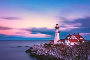 image: lighthouse on a cliff at dawn | 50 COZY MYSTERY SETTINGS to Help You In Writing a Cozy Mystery Novel (image of Alaskan town in the mountains) #cozy crime #cozy murders #cozy mystery genre #cozy mystery setting ideas #gentle reads #how to write cozy mysteries