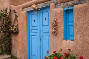 image: doorway to adobe home in Taos | 50 COZY MYSTERY SETTINGS to Help You In Writing a Cozy Mystery Novel (image of Alaskan town in the mountains) #cozy crime #cozy murders #cozy mystery genre #cozy mystery setting ideas #gentle reads #how to write cozy mysteries