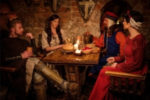 MEDIEVAL ENGLISH NAMES | photo of men and women gathered around the table, dressed as if they're in the Middle Ages in England (maybe 1400s)