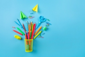 A pencil cup full of pencils, plus paper airplanes