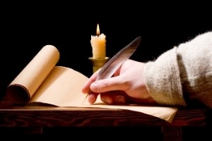 MEDIEVAL MALE NAMES FROM ENGLAND | hand holding quill and writing on a piece of parchment by candlelight