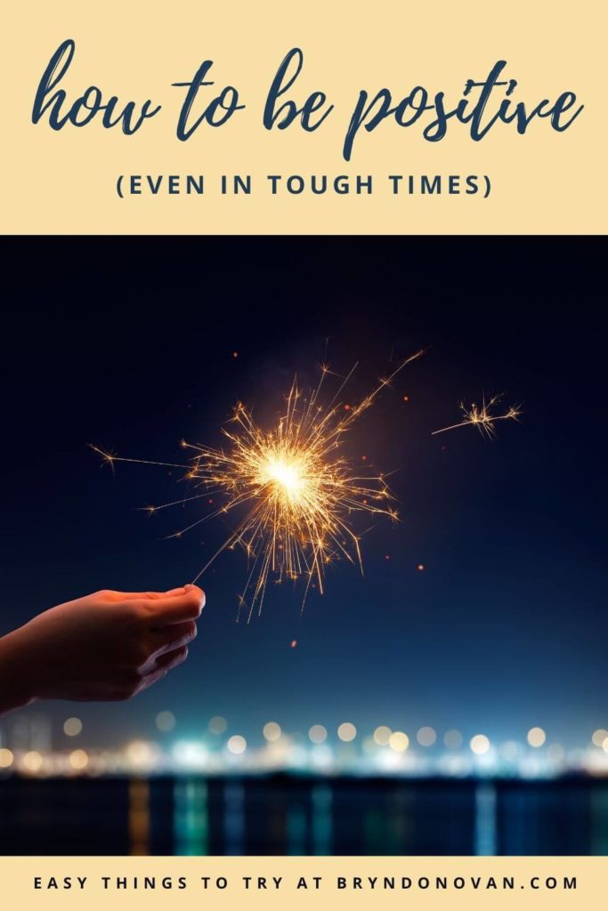 How to Be Positive (Even in Tough Times) Easy Things to Try at bryndonovan.com | hand holding a firework against a night sky (vertical Pinterest pin)