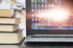 stack of books next to computer