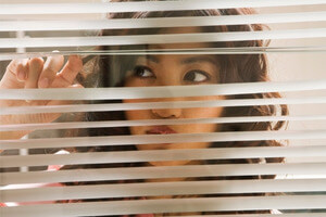 woman peering through the blinds