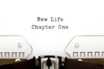 paper in typewriter, with typed words that read, "New Life, Chapter One"