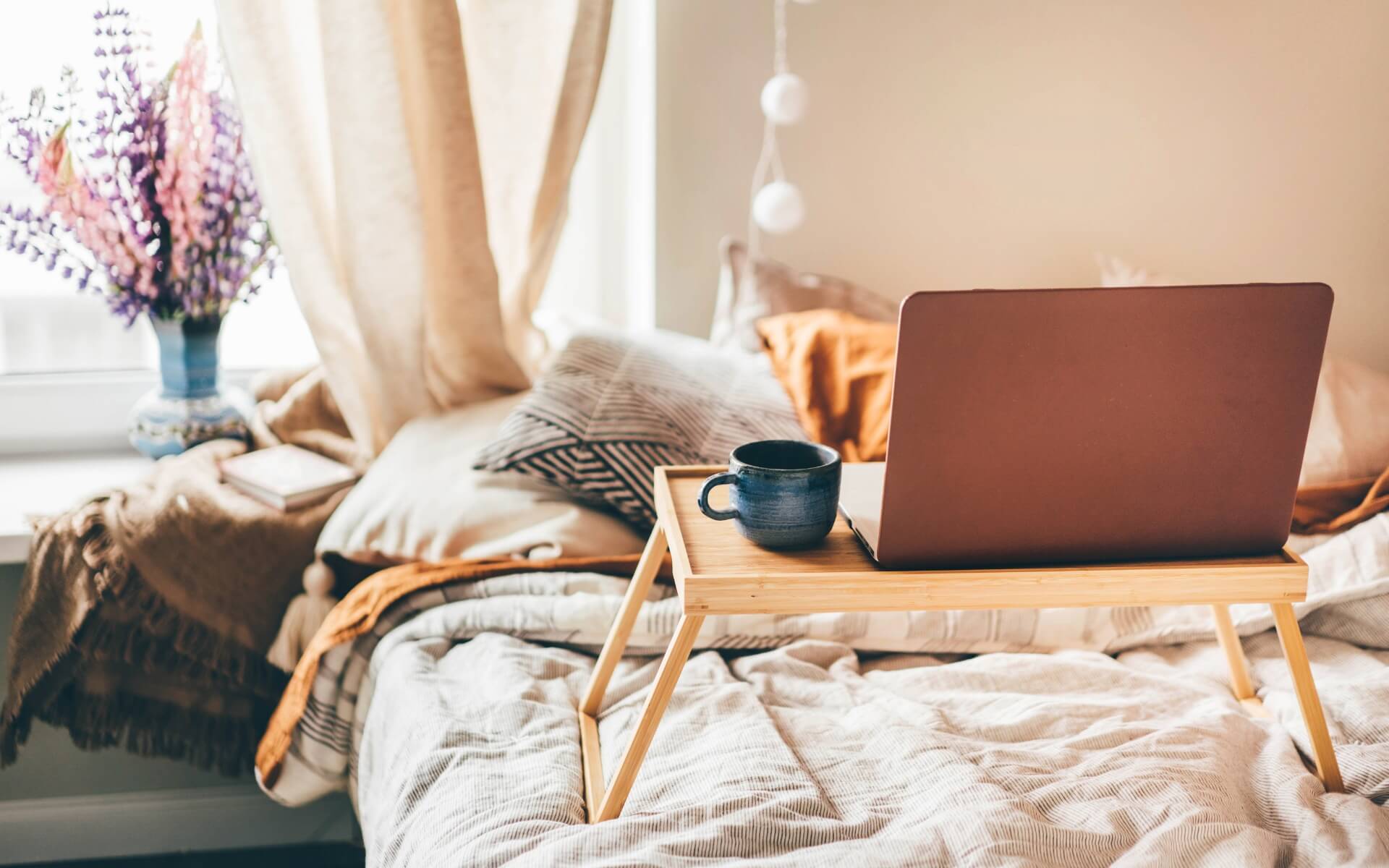 fantasy writing themes boho bedroom with laptop on breakfast tray on bed