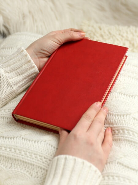 hands of a white woman holding a plain red book