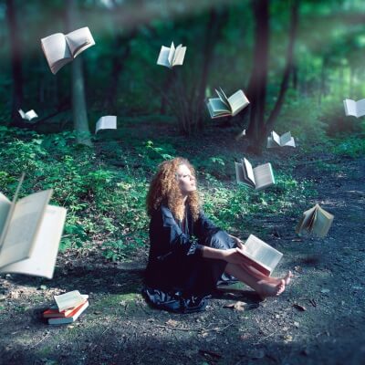 woman in a forest surrounded by flying books - how to describe a forest setting
