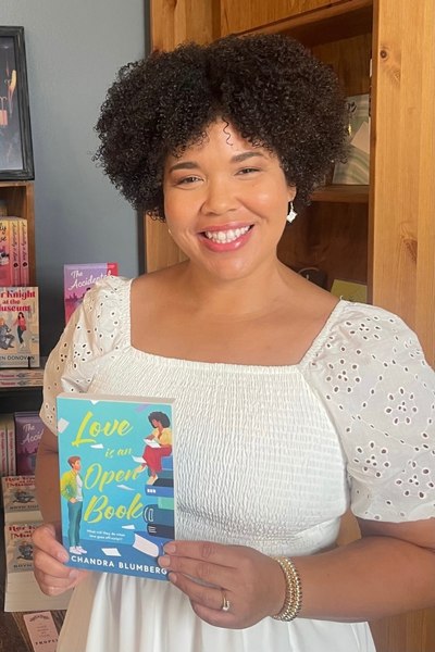 author Chandra Blumberg with her romance novel LOVE IS AN OPEN BOOK