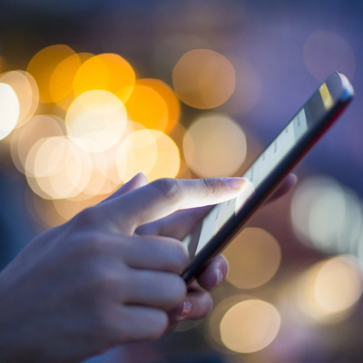 woman holding iphone at night with city lights
