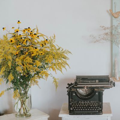 typewriter and vase full of goldenrod and black eyed Susans for WIP Wednesday August 2026