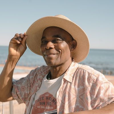 older black man at beach, wearing sun hat