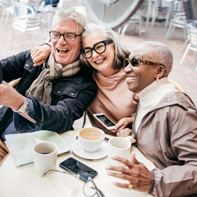 three very cool looking old people talking a selfie at a cafe