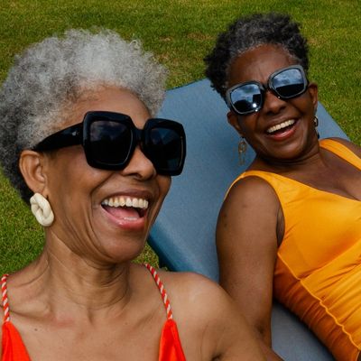two older women in swimsuits and sunglasses laughing